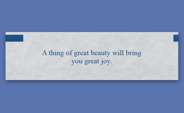 A fortune cookie slip reads, "A thing of great beauty will bring you great joy," on a white background with blue corners, set against a blue backdrop.
